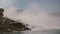 Scenic slow motion background shot of epic waters rushing down at amazing Niagara Falls waterfall under summer sky.