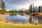 Scenic Springtime Landscape View of Distant Snowcapped Mountain Peaks, Green Grassland and Blue Lake above Canmore in Alberta