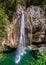 A scenic stream of a waterfall falling among a rocky gorge on the Agur river. Sheer cliffs among lush bushes and trees. Khosta