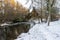 A scenic stream in winter season and snow covered ground and trees in Seaton Park, Aberdeen, Scotland