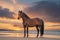 Scenic Sunset: Majestic Brown Horse Gracefully Adorns Sandy Beach Beneath Vibrant Sky.