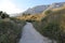 A scenic trail among field grasses, mountain slopes overlooking the mountain range Biokovo at sunset