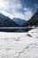 Scenic travel landscape in snowy winter scenery with fluffy soft snow covered rocks by lake lago del predil in Julian alps, italy