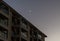 Scenic twilight scene on west Oahu, with a crescent moon over the building`s roof