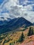 Scenic vertical rural view of evergreen mountains against a dramatic blue cloudy sky