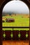 Scenic view through an arch door toward the grassy fields with wooden barns on a foggy autumn morning