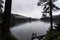 Scenic view of calm lake surrounded by hills and trees with small duck and ripples on winter day