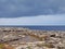 Scenic view of a coastline with rock pools on the edge of a limestone beach with bright blue calm summer sea and sunlit clouds