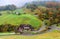 Scenic view of country roads winding between houses & colorful autumn forests on green grassy hillside in Berchtesgaden