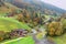 Scenic view of country roads winding between houses & colorful autumn forests on green grassy hillside in Berchtesgaden