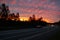 Scenic view of a curved road with cars passing under a beautiful sunset sky