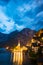 Scenic view of famous Hallstatt lakeside town reflecting in Hallstattersee lake in the Austrian Alps night time in summer,