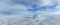 An scenic view of a frozen moutain summit with huge rocky trig point in the winter under a majestic blue sky and some white clouds