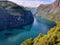 A scenic view of the Geiranger fjord in Norway taken from the Gjerdefossen viewpoint on a sunny day.