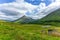 A scenic view of a grassy pyramidal Highland Scottish mountain Beinn DÃ²bhrain with grassy slope under a majestic blue sky and