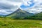 A scenic view of a grassy pyramidal Highland Scottish mountain Beinn DÃ²bhrain with grassy slope under a majestic blue sky and