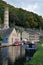 Scenic view of hebden bridge with historic buildings along the canal and moored houseboats with towpath and surrounding woodland