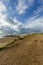 A scenic view of the Hengistbury Head beach with stony promenade and rocky groyne under a majestc blue sky and stormy clouds in