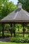 Scenic view of a landscaped wooden gazebo in a city park setting