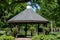 Scenic view of a landscaped wooden gazebo in a city park setting