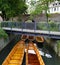 a scenic view of a little bridge, wooden boats underneath it, green trees and the old town wall in the city of Ulm in Germany