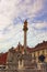 Scenic view of medieval Plague Column against cloudy sky. Ancient colorful building at the background. The Rotovz Town Hall Square