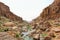 scenic view of mountain cliffs and a stoney river in the middle.