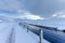 An scenic view of a moutain range in the winter with snowy slope and aqueduct under a majestic blue sky and some white clouds