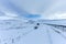 An scenic view of a moutain range in the winter with snowy slope and aqueduct under a majestic blue sky and some white clouds