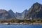 A scenic view of the North Sea with a mountain range rising above serene waters, featuring lighthouses near Moskenes in Lofoten