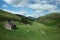 A scenic view with old scottish house, grazing sheep and a river flowing on the valley