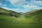 A scenic view with old scottish house, grazing sheep and a river flowing on the valley