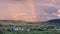 Scenic view of a rainbow over a Romanian village after summer rain, at sunset