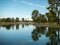 Scenic view of a reflective lake with shorelines trees under the cloudy sky