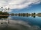 Scenic view of a reflective lake with shorelines trees under the cloudy sky