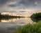 Scenic view of a reflective river with green shoreline trees at sunrise