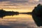 Scenic view of a reflective river with green shoreline trees at sunrise