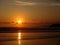 Scenic view of a sandy beach against sea waves reflecting a beautiful sunset