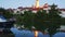 Scenic view of small French town of Dormans on bank of Marne river overlooking illuminated tower of Saint-Hippolyte