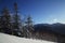 Scenic view of snow-covered fir trees and woody hills on a background.