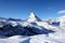 Scenic view on snowy Matterhorn peak in sunny day with blue sky and some clouds in background