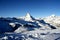 Scenic view on snowy Matterhorn peak in sunny day with blue sky and some clouds in background