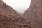 Scenic view of the stone outcrops on brown rocky hills on a misty day