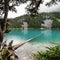 Scenic view of tree logs floating on a glacial lake against mountains on a cloudy day