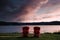 Scenic view of two red benches on the shore of a tranquil lake against hills at pink sunset
