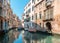 Scenic View of Venetian Canal with Boats under Blue Sky in Venice, Italy