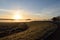 A scenic view of a winding Dutch road overlooking a meadow filled with ground frost close to Oss, netherlands