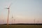 Scenic view of windmills working in a field during sunset