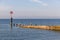 A scenic view of a wooden groyne with several seagulls along a majestic blue sea under a blue sky and some white clouds