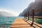 Scenic view on wooden planks pier with railings built on northern shore of beautiful Garda lake in Lombardy, Italy surrounded by